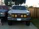 1986 Ford Bronco - Front view of a 1986 Ford Bronco with KC lights and smiley face covers. A second vehicle is parked to the left.