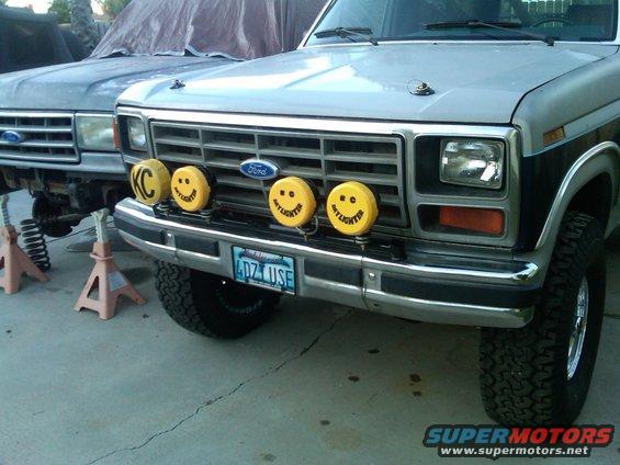 Silver and black Ford truck front end with KC lights and smiley faces