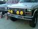 1986 Ford Bronco - Two Ford trucks are parked outside, one with yellow KC lights on its grille.