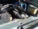1986 Ford Bronco - Engine bay of a 1986 Ford Bronco, blue hoses and a black brace.