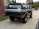 1986 Ford Bronco - This lifted 1986 Ford Bronco is parked in a driveway, showing its rear end and custom off-road modifications.
