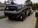 1986 Ford Bronco - A two-tone Ford Bronco is loaded onto a tow truck, with a house and fence in the background.