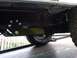 1986 Ford Bronco - The underside of a 1986 Ford Bronco reveals custom suspension parts and BFGoodrich All-Terrain tires, indicating off-road enhancements.