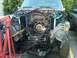 1986 Ford Bronco - The front end of an SUV is disassembled, revealing the engine and transmission area, with repair equipment present.