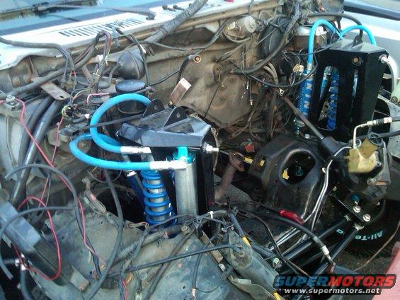 Engine bay with blue suspension components and wiring. Some text on shocks reads 'KING'