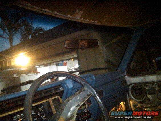 Blue interior of a car with a steering wheel and dashboard visible. The headliner is damaged