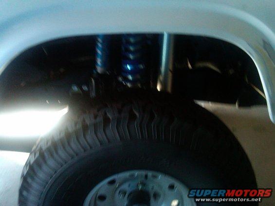 Close-up of a tire and blue shock absorber in a vehicle's wheel well