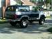 1986 Ford Bronco - This two-tone Ford Bronco is parked in a residential driveway, showing its side and rear profile.