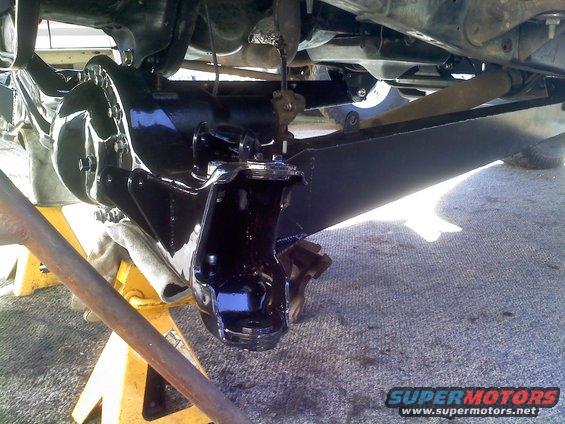 Vehicle undercarriage with black painted differential and suspension components supported by yellow jack stands