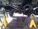 1986 Ford Bronco - The rear axle assembly of a vehicle is elevated on jack stands, with brake calipers detached and lying on the ground.