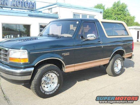 Dark green Ford Bronco with tan trim, parked in front of a building