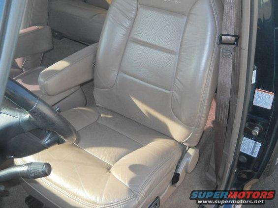 Front passenger seat and dashboard of a vehicle. The seat is tan leather with armrests