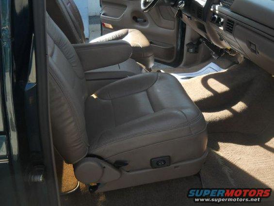 Interior shot of a vehicle's front seats, showing tan leather upholstery and armrests