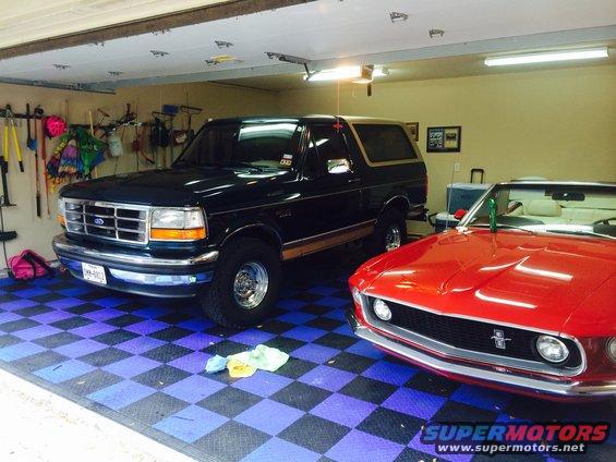 Dark blue 1994 Ford Bronco parked in garage next to red convertible
