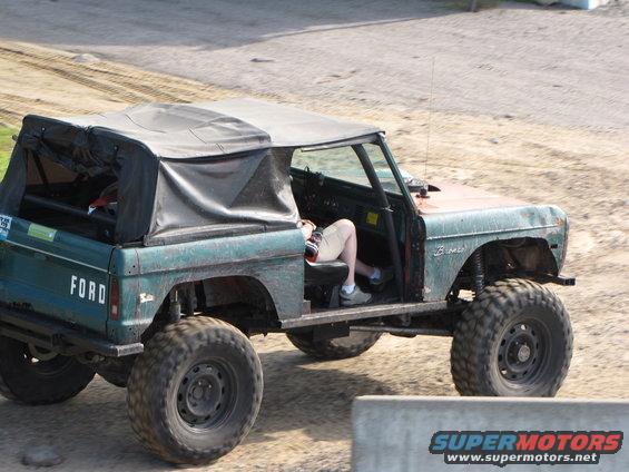 Green 1979 Ford Bronco with soft top and large tires, side view