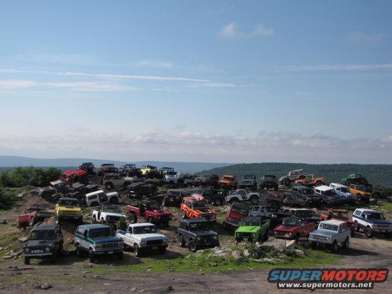 1979 Ford Bronco and other off-road vehicles parked on a hill under a blue sky