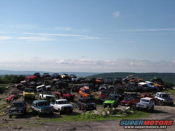 Many SUVs and trucks parked on a hillside