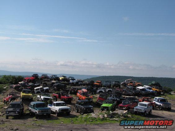 Group of 1979 Ford Broncos parked on a rocky hill under a blue sky