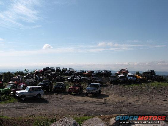 Silver 1978 Ford Bronco parked on a dirt lot with many other off-road vehicles