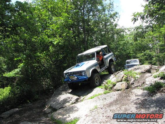 White and blue 1979 Ford Bronco climbing rocks on a trail