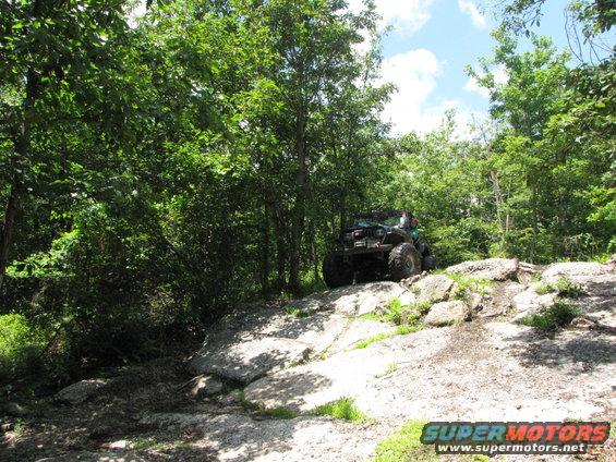 Off-road vehicle climbing rocks on a wooded trail