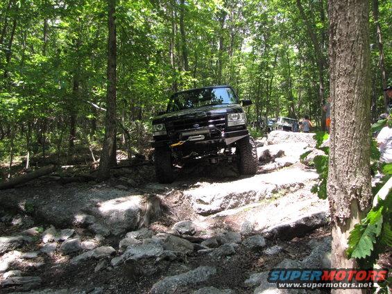 Black SUV with winch and custom bumper navigating a rocky trail