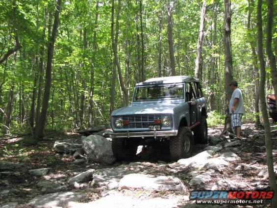 Blue 1979 Ford Bronco on a rocky forest trail