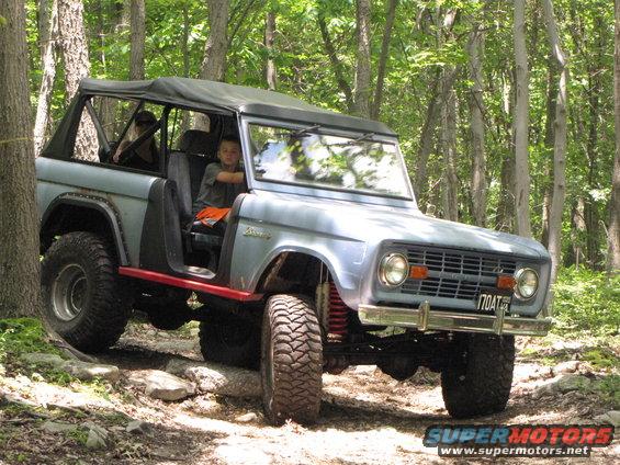 Light blue off-road SUV with soft top on rocky trail. License plate reads 170AT