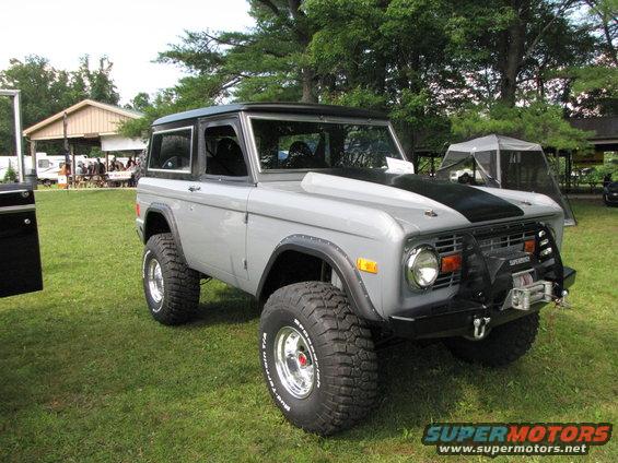 Gray Ford Bronco with black hood stripe and winch on front bumper, parked on grass