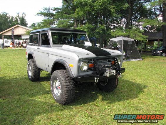 Gray 1978 Ford Bronco with black hood stripe, lifted suspension, and winch on front bumper parked on grass