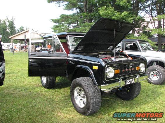 Black 1979 Ford Bronco with hood open and driver's door ajar