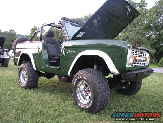 Green and white Ford Bronco with hood open, off-road tires, and aftermarket bumper