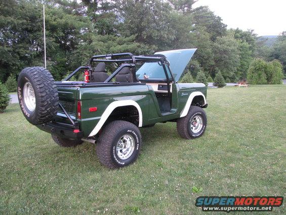 Green 1979 Ford Bronco with spare tire mounted on rear bumper and hood open