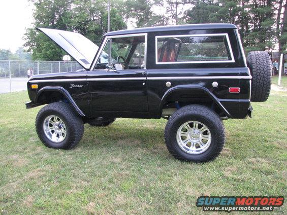 Black Ford Bronco parked on grass, hood is up, spare tire mounted on rear door