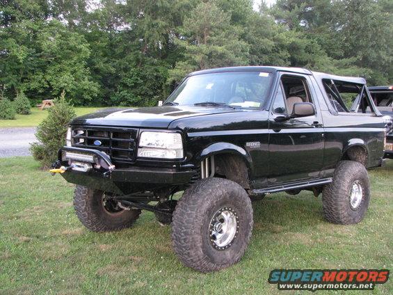 Black lifted Ford Bronco with aftermarket bumper, winch, and roll cage visible
