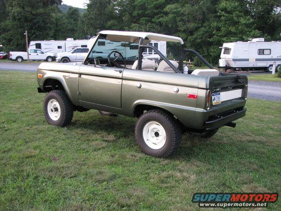 Green 1978 Ford Bronco with a white top and white wheels parked on grass