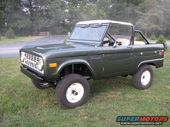 Green 1979 Ford Bronco with white top and white wheels, 3/4 front view