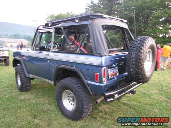 Blue 1978 Ford Bronco with a roof rack and spare tire, parked on grass