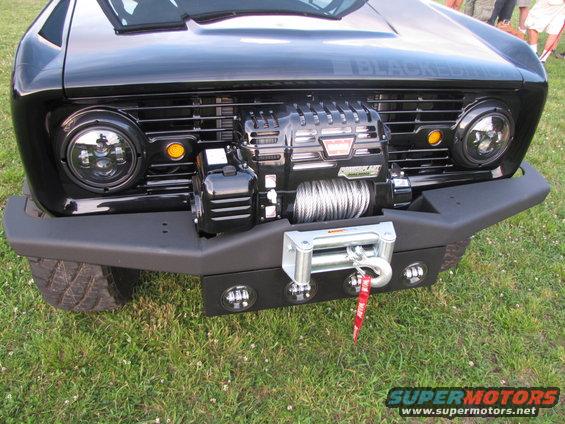 Black Ford Bronco front end with a large winch mounted on the bumper and a supercharger visible behind the grille