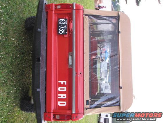 Red 1978 Ford Bronco rear view with a tan soft top and license plate 63-735