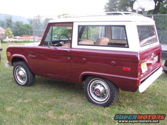 Maroon and white Ford Bronco parked on grass. "Bronco" script on fender