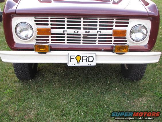 Maroon and white vehicle front with prominent grille and 'FORD' license plate