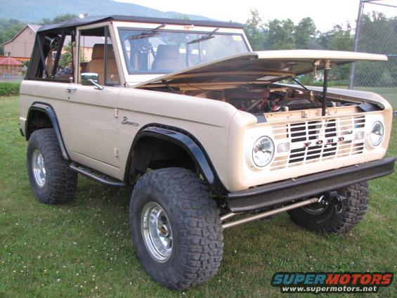 1979 Ford Bronco with hood open, showing engine. Tan exterior, black soft top