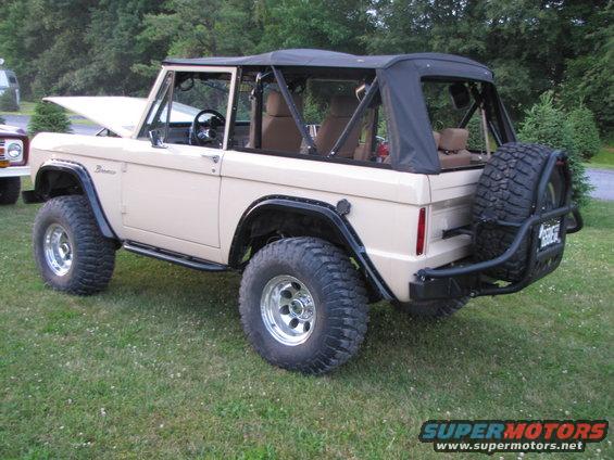 Tan 1979 Ford Bronco with a black soft top and spare tire on the rear bumper