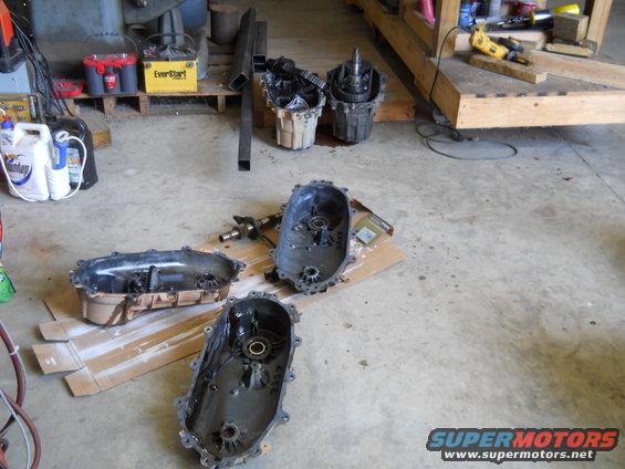 Disassembled transfer cases and related parts on a garage floor