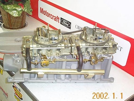 Dual carburetors mounted on a Ford intake manifold, with a Motorcraft Ford box in the background