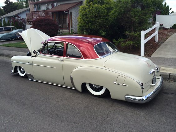 Cream and red coupe with hood open, lowered suspension, whitewall tires