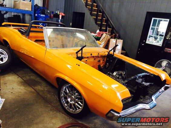 Orange convertible with hood open, undergoing restoration