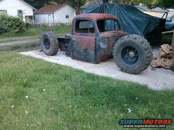 Old pickup truck body, missing fenders and hood, on large off-road tires