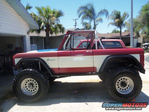 Red and white Ford Bronco with off-road tires parked in a driveway
